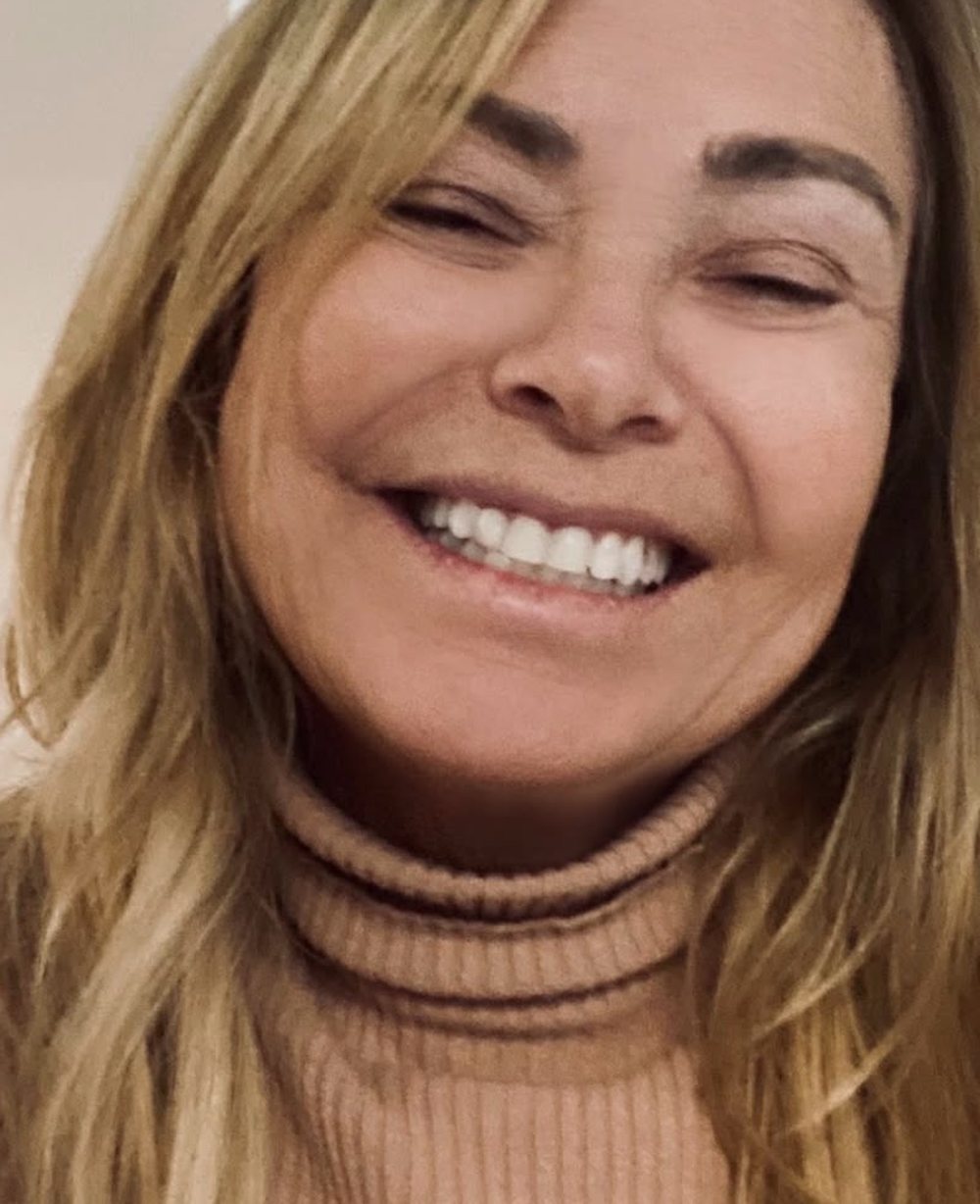 Retrato de Cristine Dias sorrindo em casa.